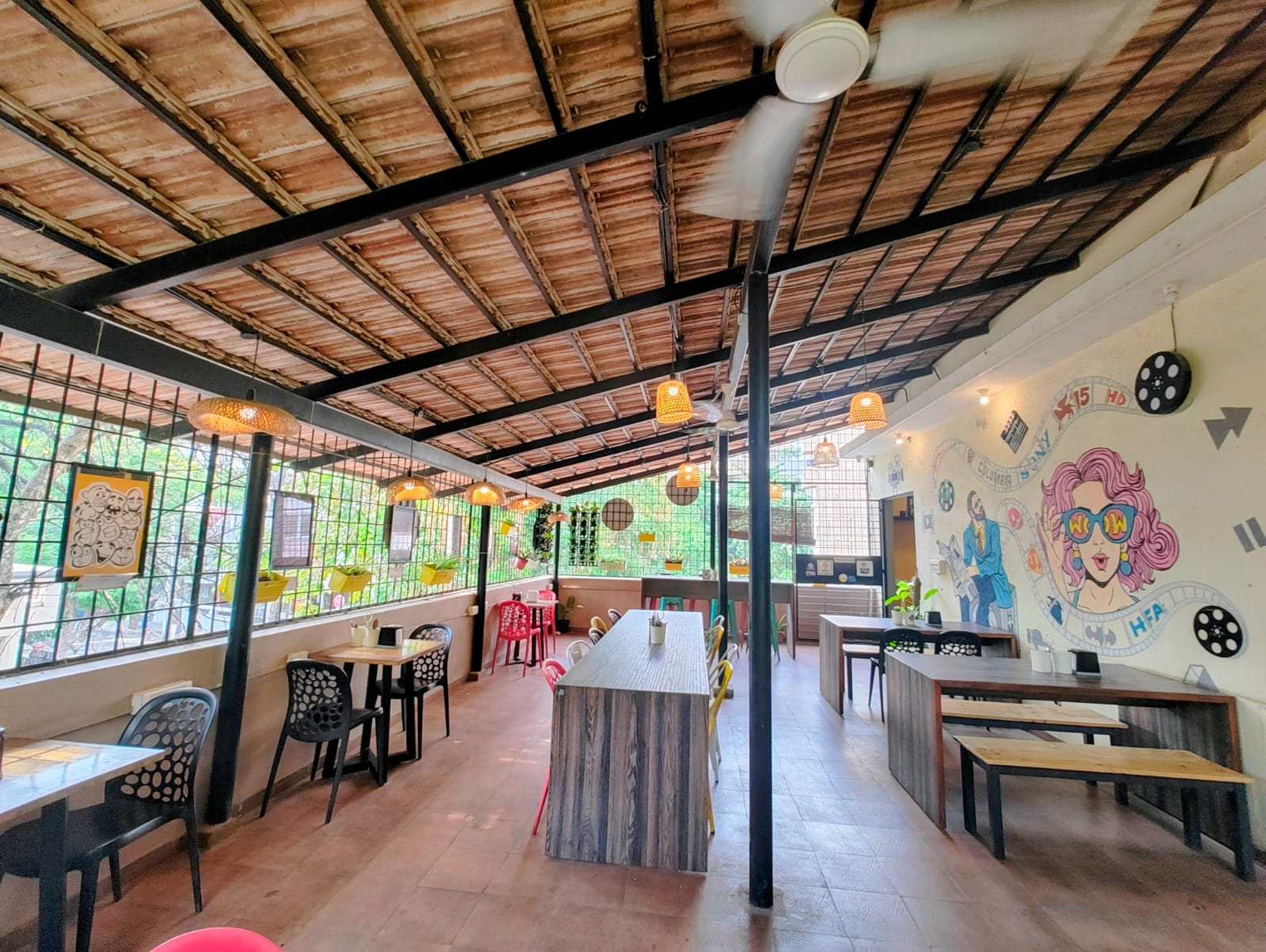 Bright and airy open seating area with artistic wall murals and hanging lights, perfect for coffee brewing workshops in Koramangala.