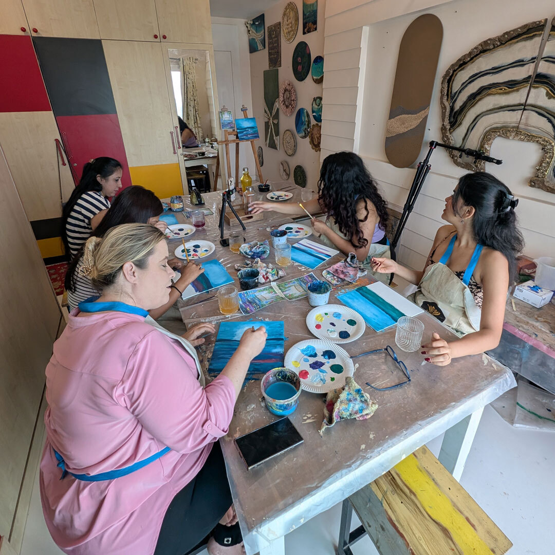 Participants engaged in painting at a communal table, enjoying a relaxed sip and paint experience.