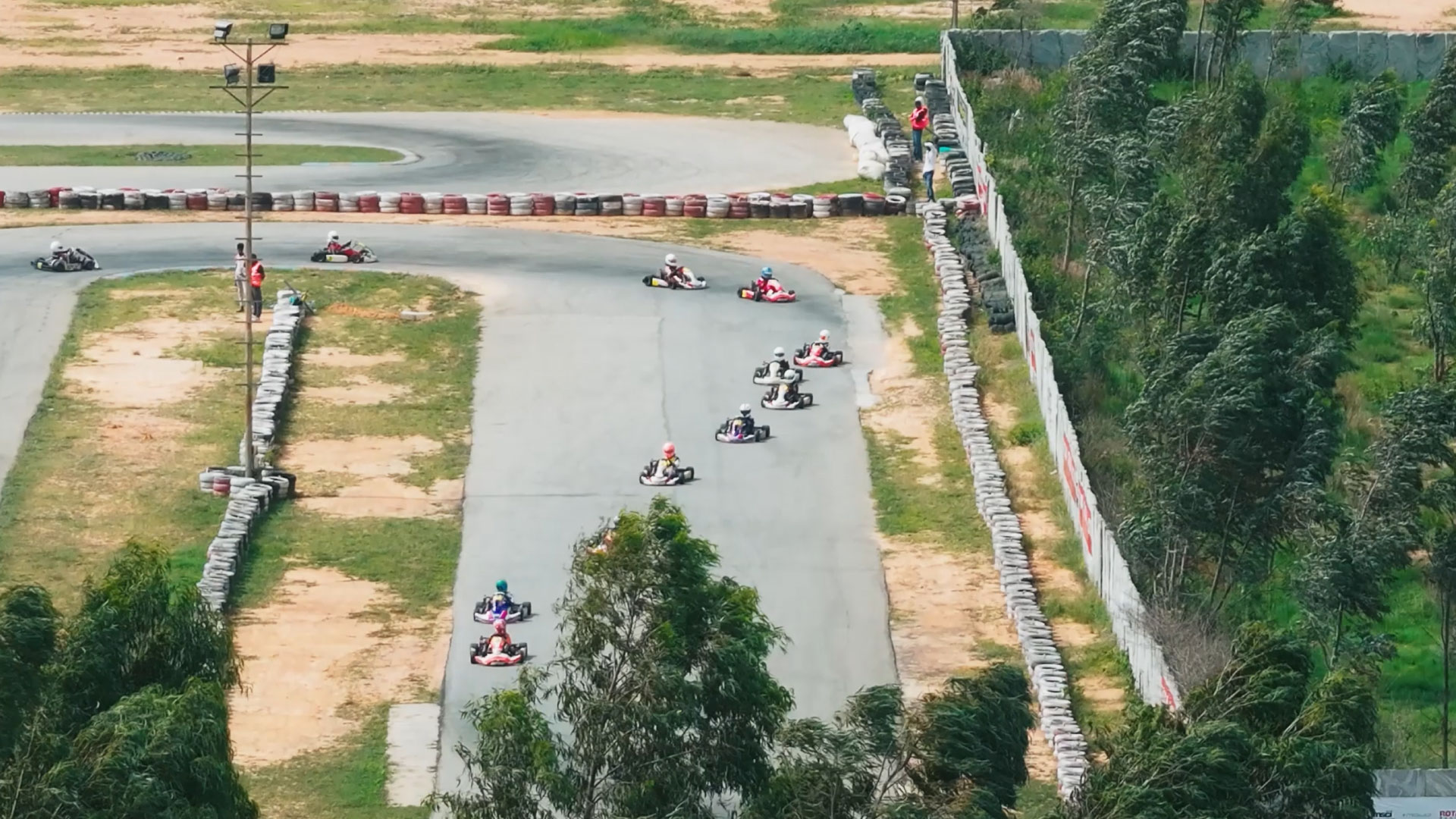 An aerial view of a go-kart track with several karts racing on the circuit.