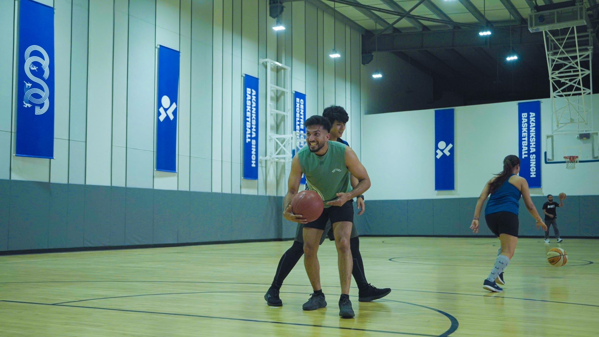 Female player lining up for a basketball shot with male player nearby at indoor court in Bengaluru.
