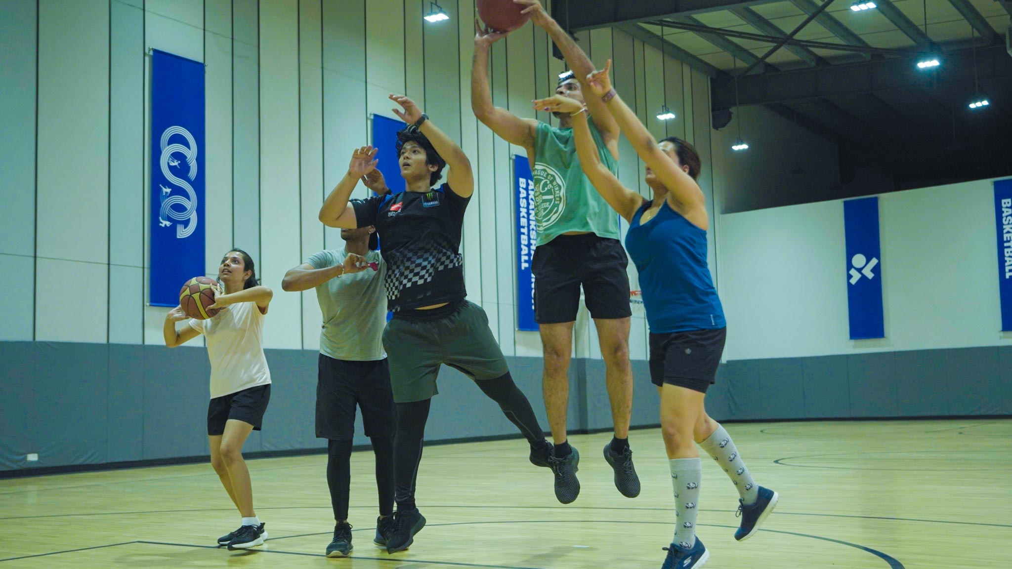Several players contesting for the basketball on a Bengaluru indoor court during a game.