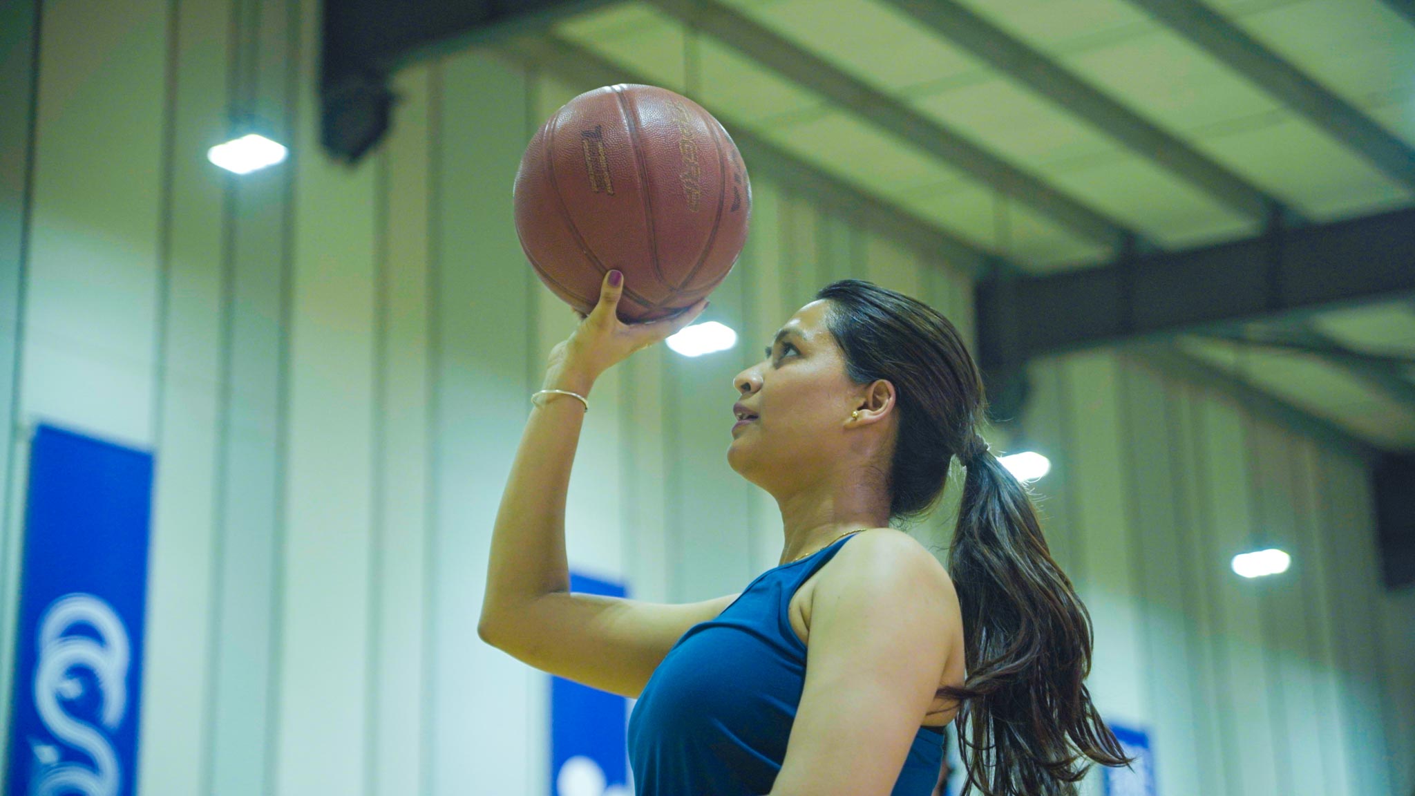 Players in action on indoor basketball court, focused on shooting and defending.