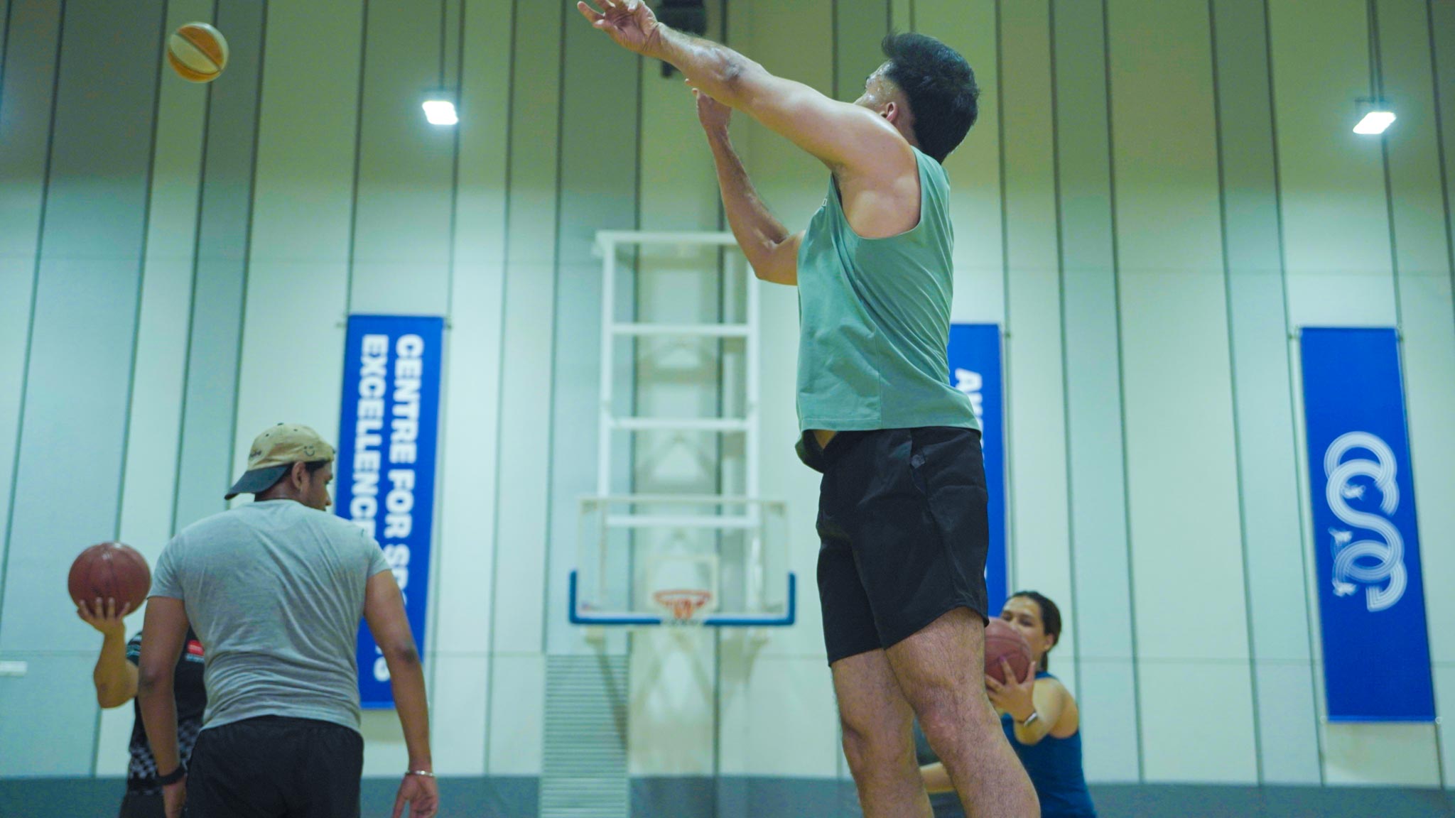 Player in green jersey shooting a basketball indoors at Bengaluru’s best basketball experience.