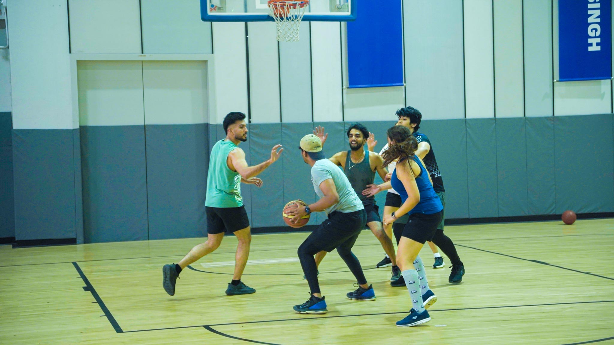 Group of players on indoor basketball court preparing to play, focused on the game.