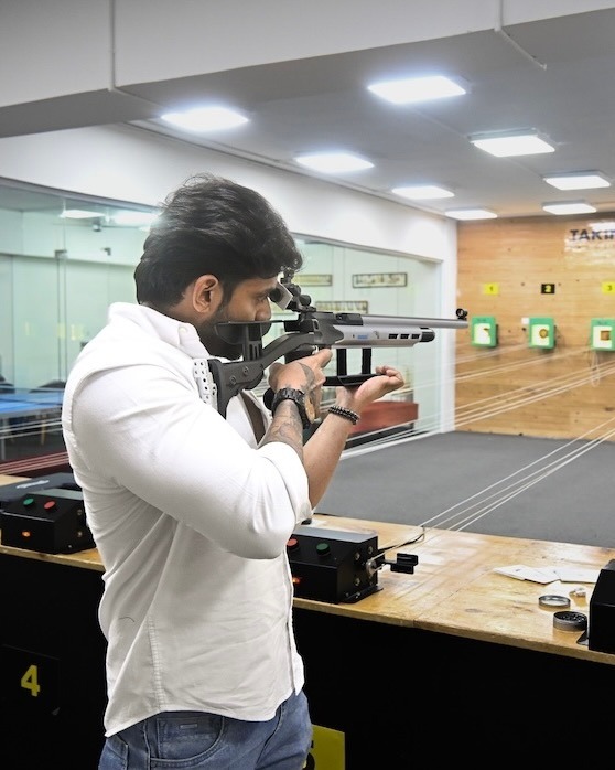 Man aiming a rifle with focus at a shooting range in Electronic City, Bengaluru.