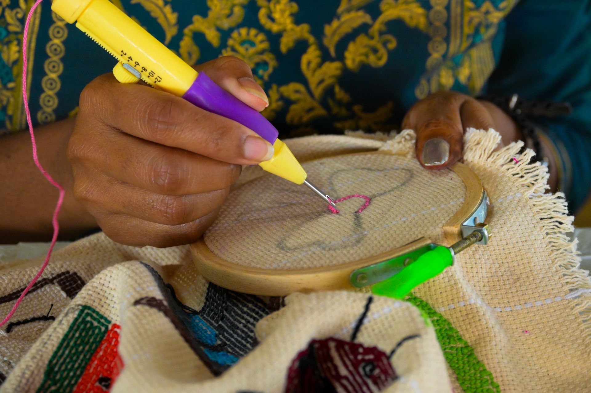 Detailed view of punch needle embroidery tool creating thread loops on fabric in a hoop.