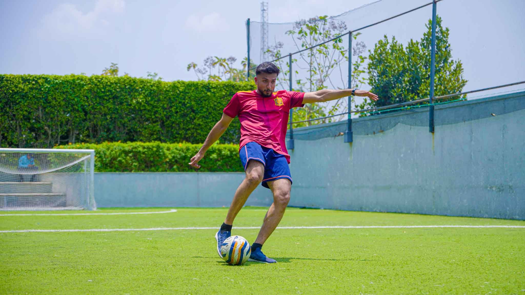Soccer player kicking ball outside with teammates and goalpost in background during The Ultimate Weekend Playday.