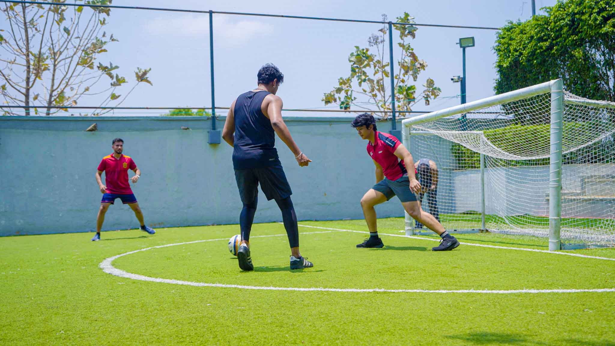 Men playing outdoor soccer near goalpost on green field during The Ultimate Weekend Playday.