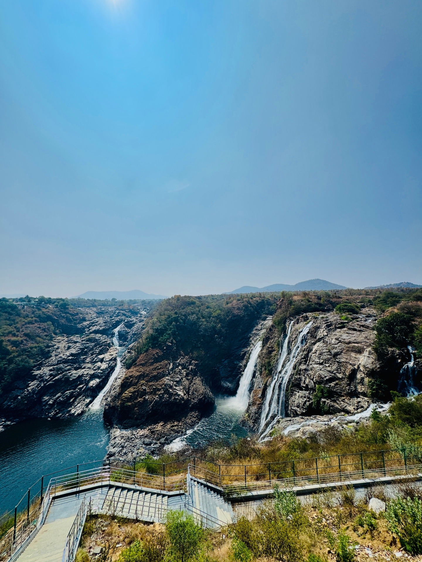 Scenic waterfall and rocky landscape with clear blue sky, perfect for a farm day out near Bengaluru.