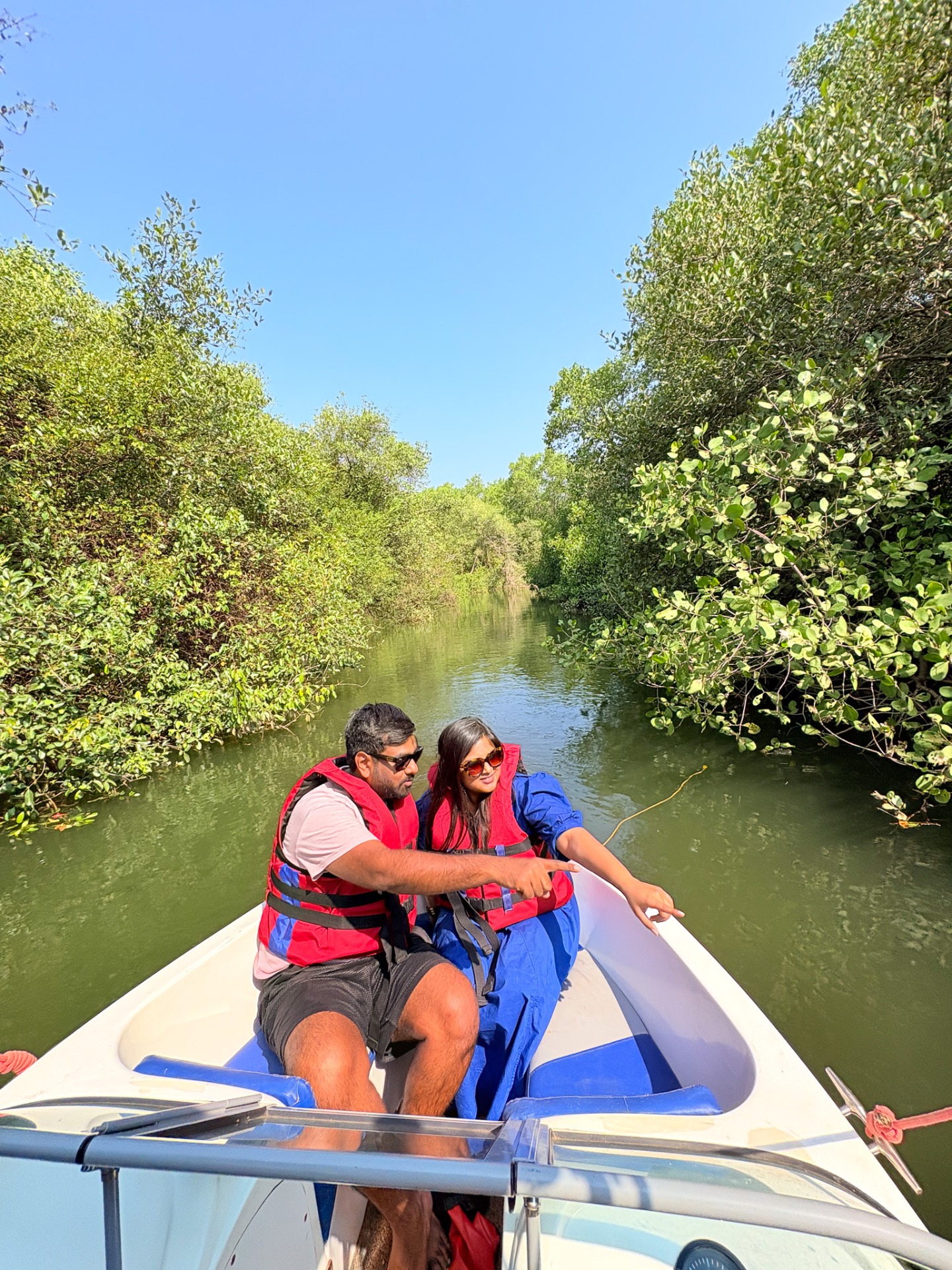 Couple wearing life jackets enjoying scenic boat ride through green mangroves during Royal Goan Escape.