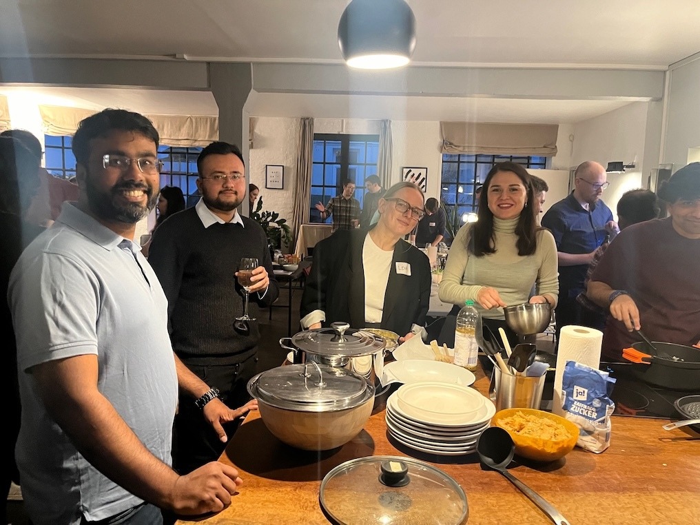 Group of people gathered around kitchen counter with cooking utensils and plates during Team MasterChef Challenge