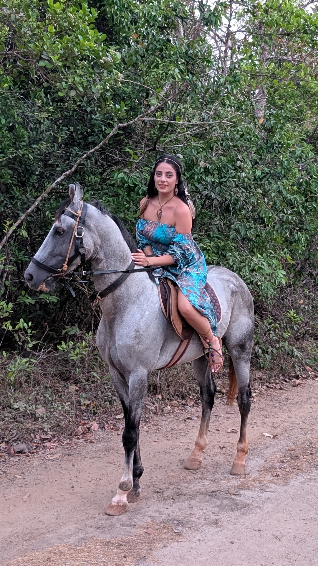 A woman in blue dress sitting on a grey horse surrounded by dense green jungle during Goa hidden jungle horse ride.