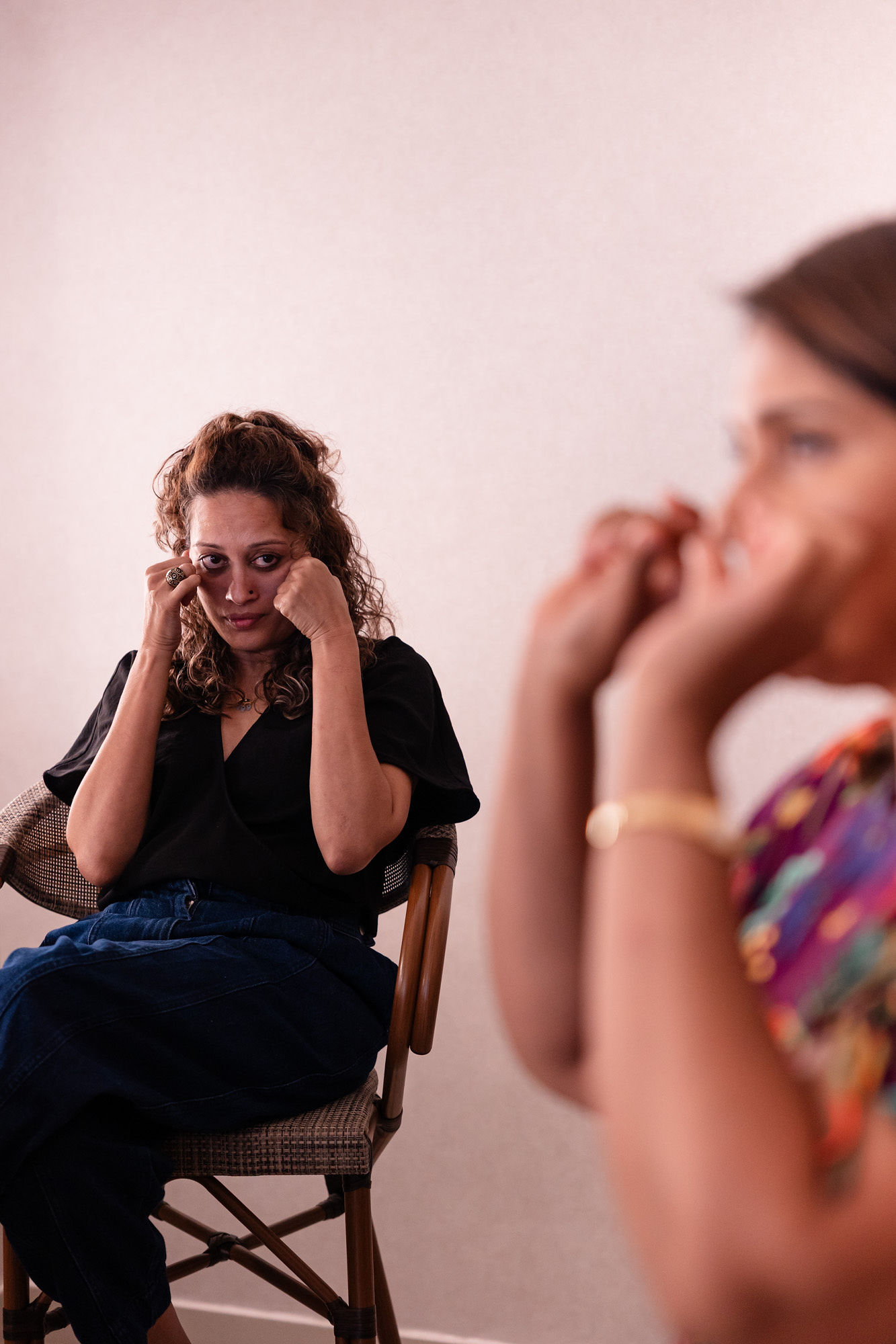 Women practicing facial massage or makeup techniques seated and following instructions from the trainer.