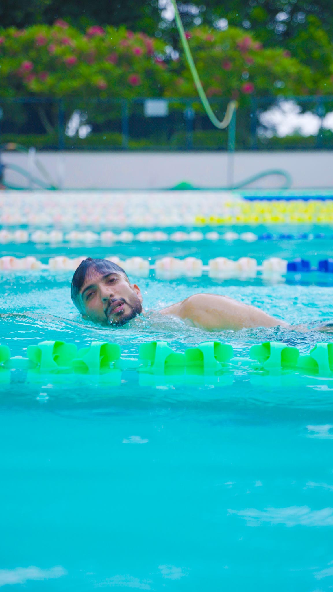 Man swimming freestyle in outdoor pool concentrating during The Ultimate Weekend Playday.