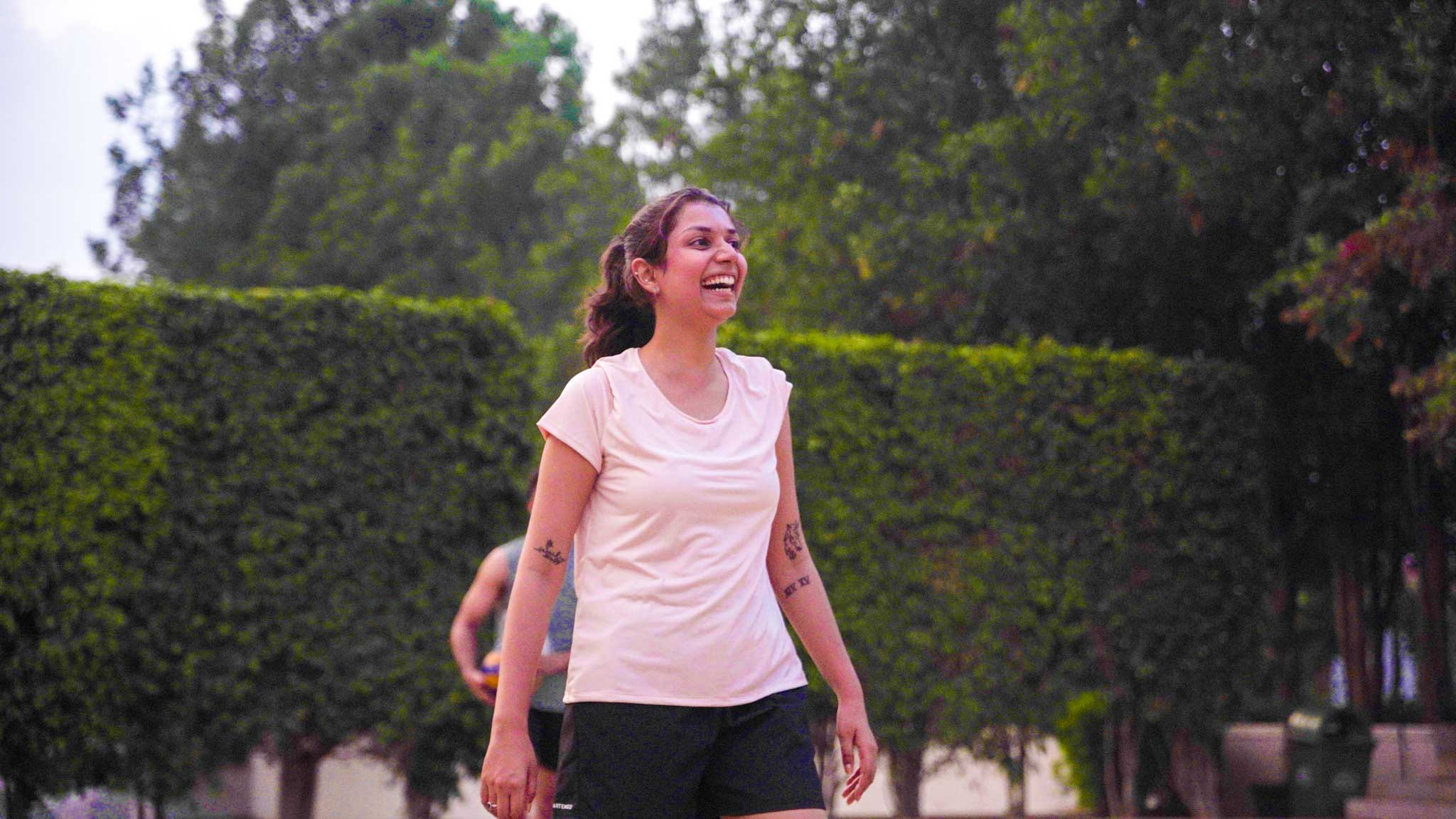Smiling woman standing on volleyball court during The Ultimate Weekend Playday.