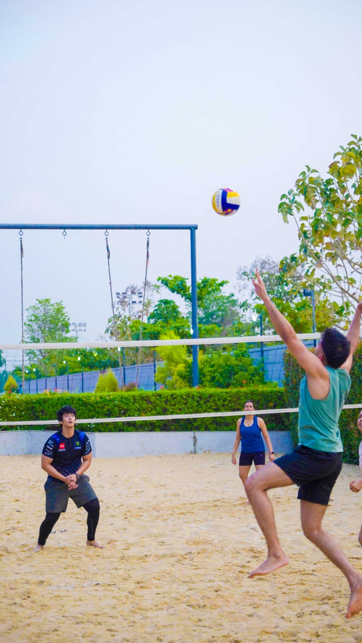 Players on a sandy volleyball court focused on incoming ball during a match.