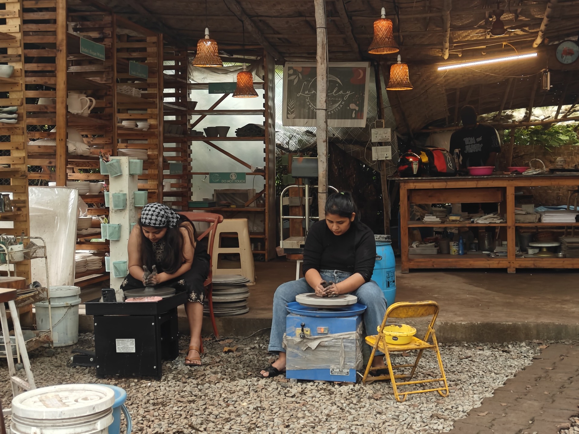 Pottery class participants shaping clay on pottery wheels in a natural light studio space.