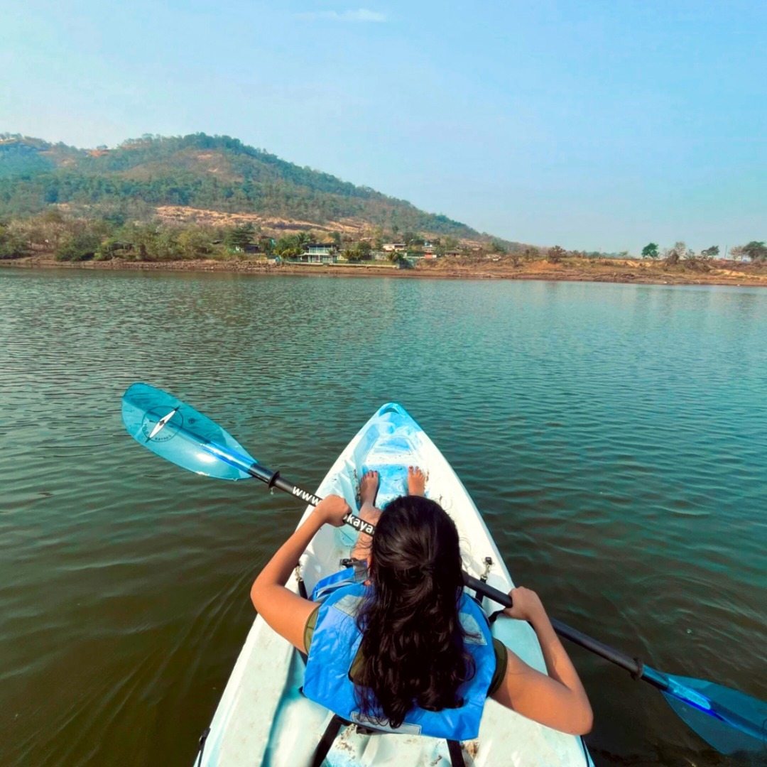 Person kayaking on calm lake surrounded by hills on a sunny day during fun day out in nature.