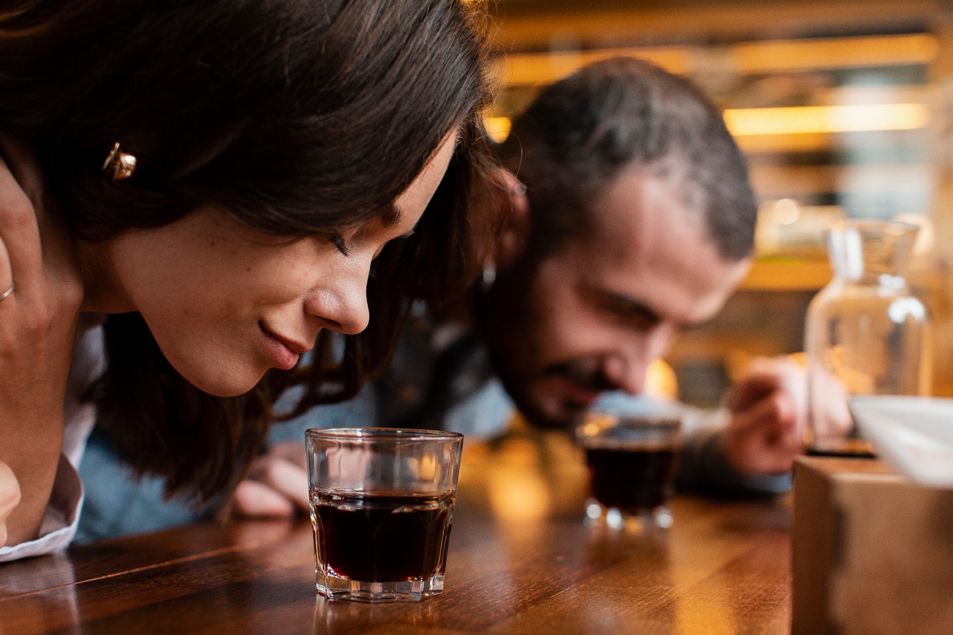 Couple smelling aroma of coffee in several cups arranged on a wooden table.