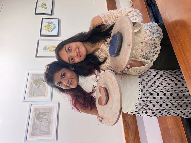 Two women showing their handmade trinket dishes smiling.