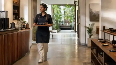 Standalone gallery: Show a guide walking a small tray of coffee courses toward the tasting area,.