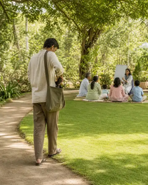 Standalone gallery: a single adult walks slowly along the edge of the green gathering area while.