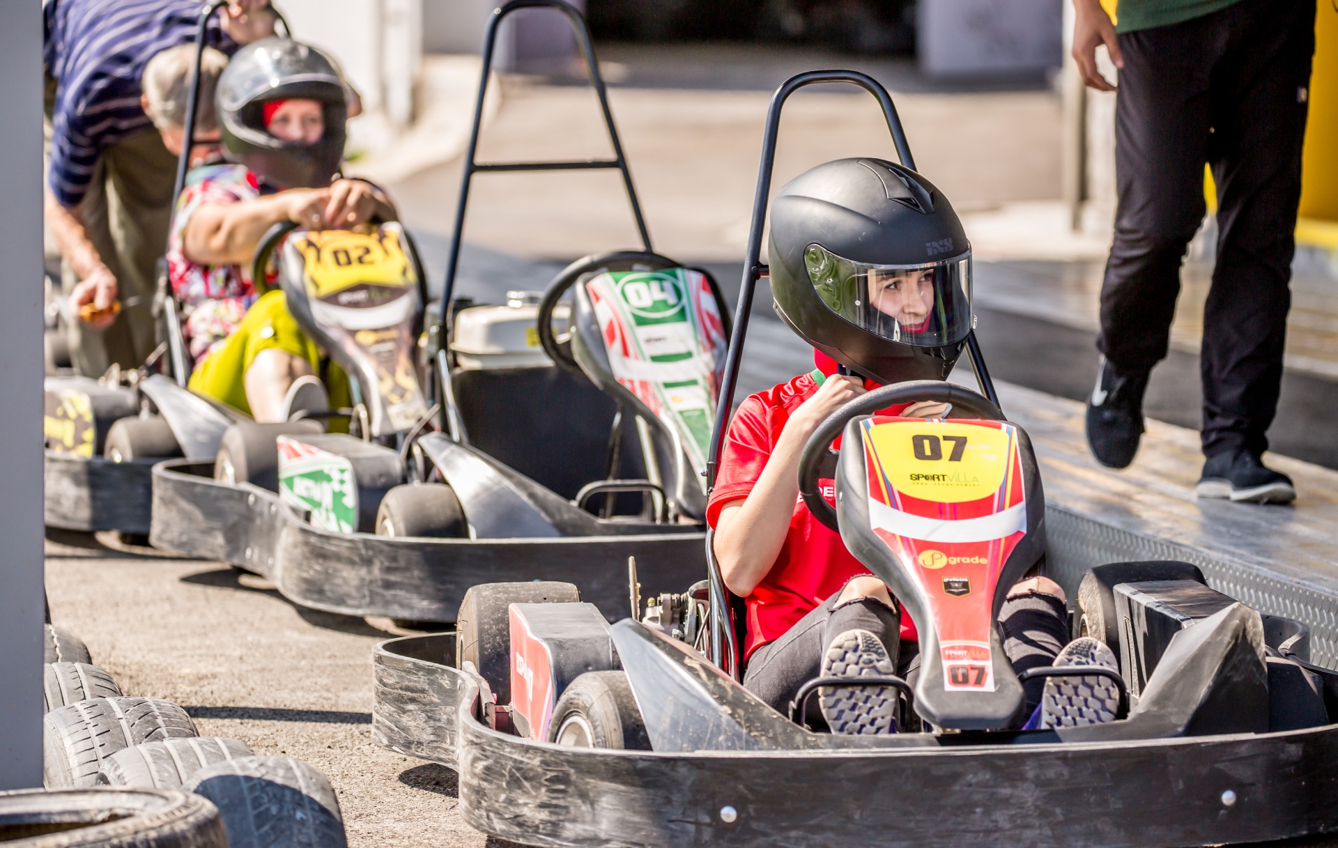 Couple enjoying go-kart racing, wearing helmets and driving closely together on the track.