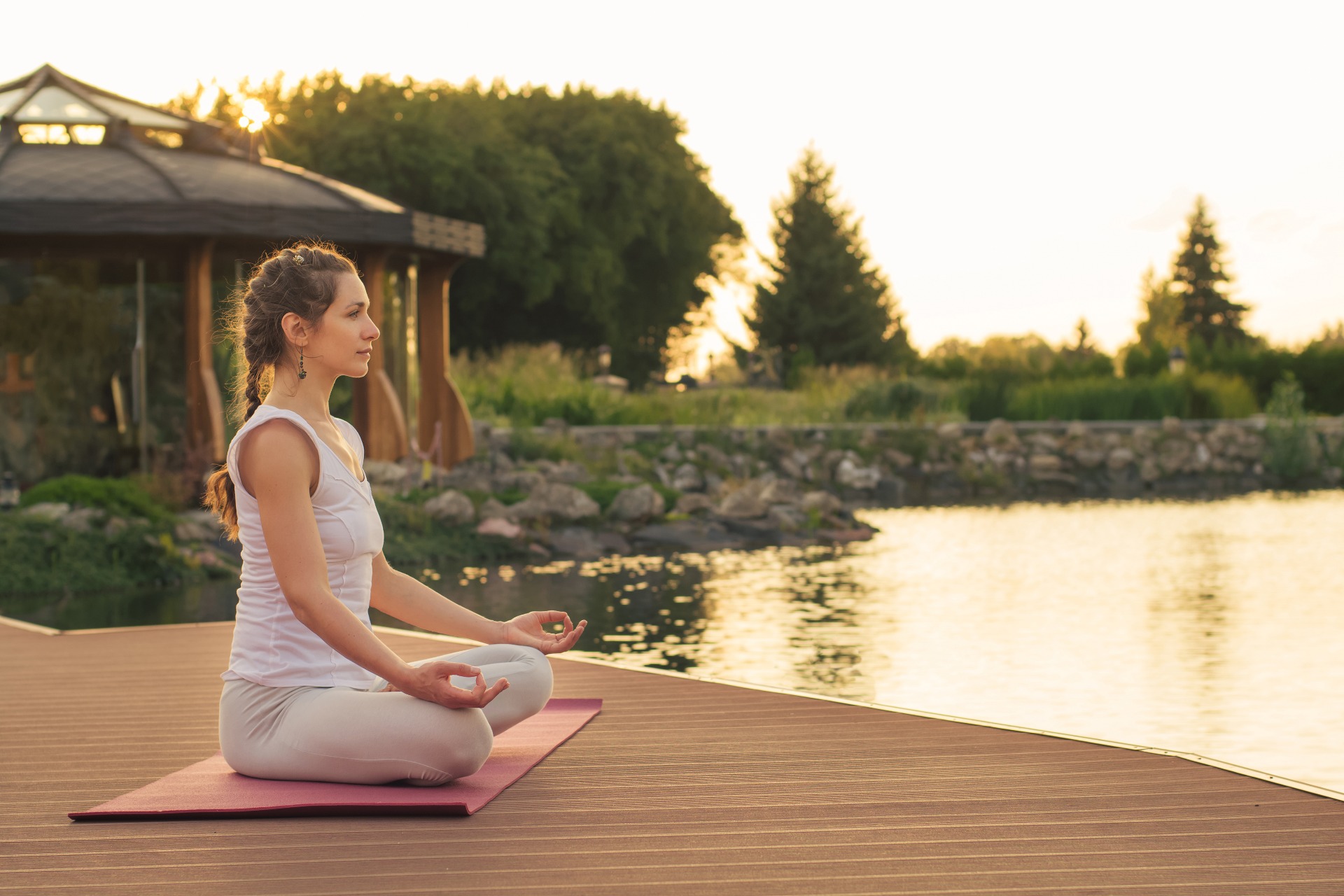 Woman practicing meditation at sunset overlooking the water